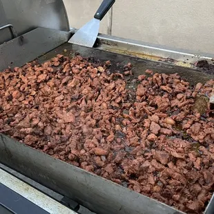 a grill with a large amount of meat being cooked