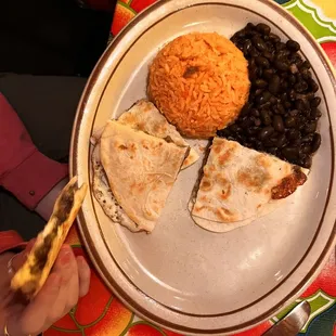 Child&apos;s quesadilla with black beans minus the slice of quesadilla already being munched.