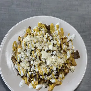 Loaded pub fries. French fries topped with our house made tzatziki and Greek dressing, feta cheese, mustard and your choice of meat.