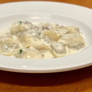 Tortellini alla Crema con Funghi. Our tortellini is made fresh and all shaped by hand. Served with mushrooms in a light cream sauce