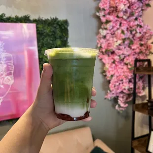 a hand holding a cup of green tea