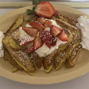 a plate of french toast with strawberries and whipped cream