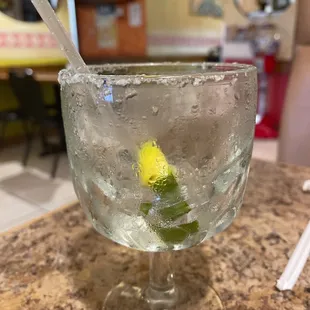 a glass of water with a lime slice in it