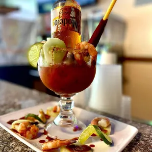 a bloody cocktail with shrimp, cucumber, and lime
