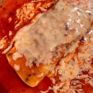 two enchillas covered in sauce and cheese