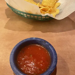 a bowl of salsa and a basket of tortillas