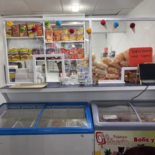 Counter where drinks and desserts are served. A couple of freezers with natural flavored popsicles.