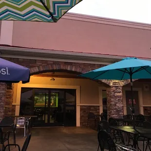 the outside of a restaurant with tables and umbrellas