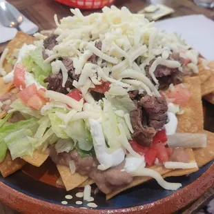 a plate of nachos with meat and cheese