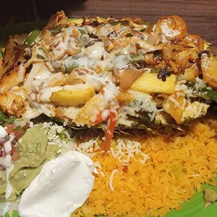 Pina Hawaiana - fresh pineapple half stiffed w shrimp, scallops, crab meat, peppers, tomatoes and pineapple bits; covered in melted cheese