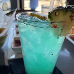 a blue drink with a pineapple garnish
