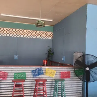a bar with a fan and chairs