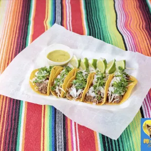 Beef Asada Street Tacos, topped with Monterrey Jack Cheese, onions, cilantro with limes and salsa verde on the side.