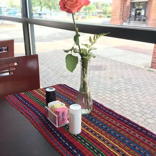 a rose in a vase on a table
