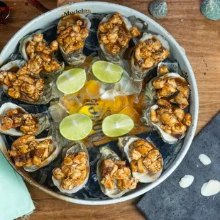 a bowl of oysters with lime wedges