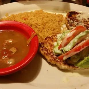 Chicken Milanesca which is lightly breaded chicken breast with avocado slices and tomato served with beans and tortillas.