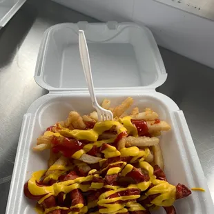 a container of fries with mustard and ketchup