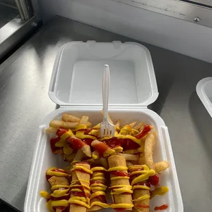 a container of hotdogs with mustard and ketchup