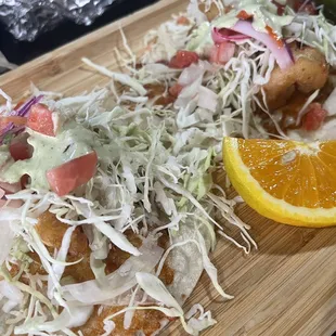 a wooden cutting board with a taco and a slice of orange