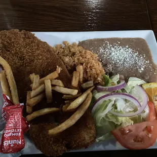 Fish filet with beans, rice, crispy fries, and a small salad.