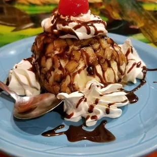 a blue plate topped with ice cream, chocolate sauce, and a cherry