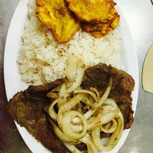 Un rico Arroz blanco, con Bistec encebollado y tostones.