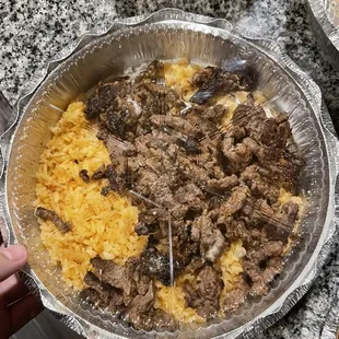 a hand holding a pie pan filled with food