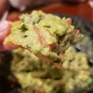 a hand holding a piece of guacamole