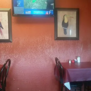 two tables with red tablecloths and a television mounted on the wall