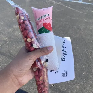 a hand holding a bag of beans and a tube of cream
