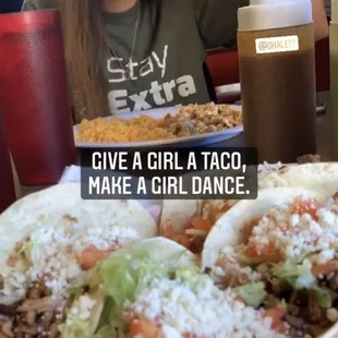 a woman sitting at a table with a plate of tacos