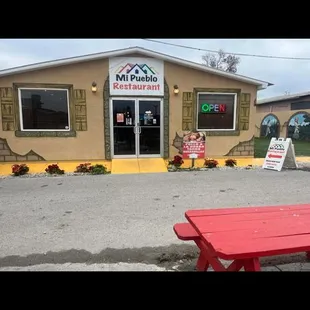 a red picnic table in front of the restaurant