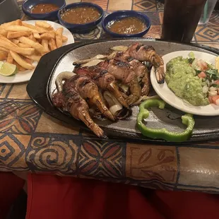 Camerones Bacon wrapped shrimp fajitas with a side of fries.
