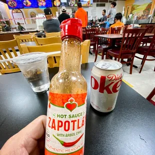 a hand holding a bottle of hot sauce