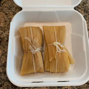 two tamales wrapped in corn