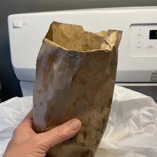 a hand holding a brown paper bag