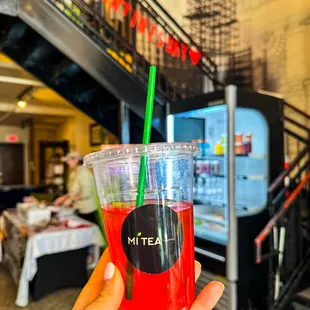 a hand holding a drink with a straw