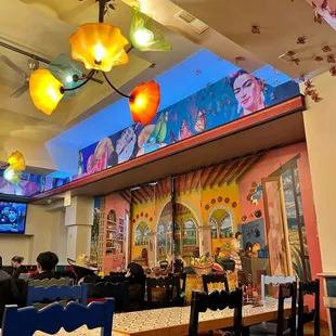 a restaurant with a colorful mural on the ceiling