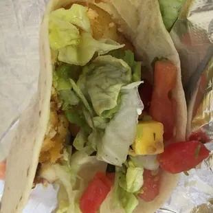 a taco with lettuce, tomatoes and corn