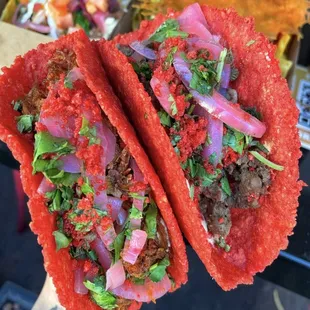 a hand holding two tacos