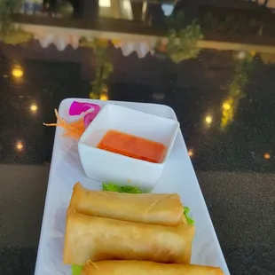 a plate of spring rolls with dipping sauce