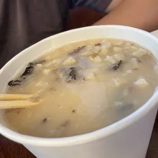 a bowl of soup with chopsticks