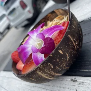 a coconut bowl with strawberries, strawberries, and a flower