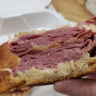 a person holding a sandwich in a styrofoam container