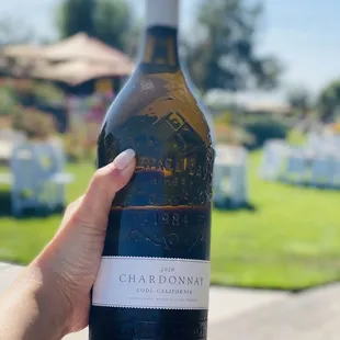 a hand holding a bottle of chardonnay