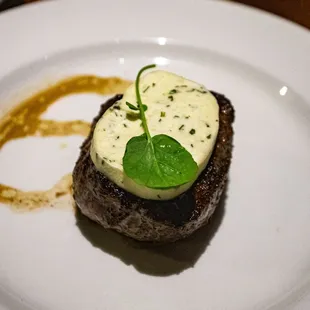 a piece of steak topped with sauce