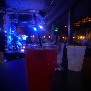 a glass of red liquid and a plastic cup of ice