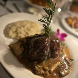 a plate of meat with gravy and mashed potatoes