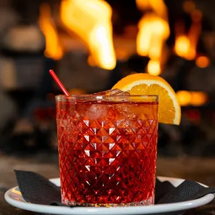 a red cocktail with a slice of lemon