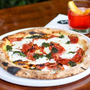 Now serving Napoli style wood-fired pizzas like this Chef's Pizza w/ pesto, mozzarella, and Calabrese piccante. Paired with a Negroni!